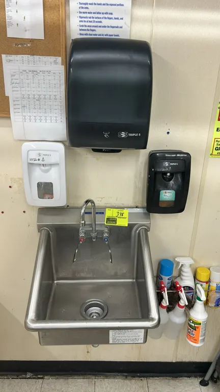 Stainless steel handwashing sink. Features side splash guards, gooseneck faucet with wrist-blade handles, and basket drain. Includes Triple S paper to