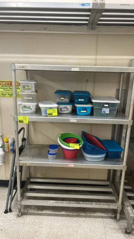 Metal 4-tier shelving rack. Features (3) solid metal shelves and (1) bottom slatted tube shelf. 48" x 20". Contents not included.