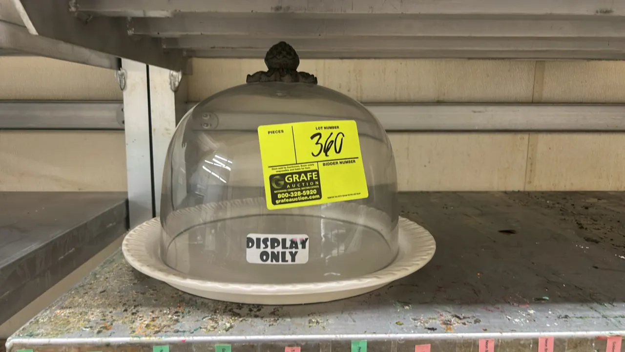Glass cake display dome with ceramic plate base. Features a clear dome with a decorative finial handle and a round fluted ceramic base tray.