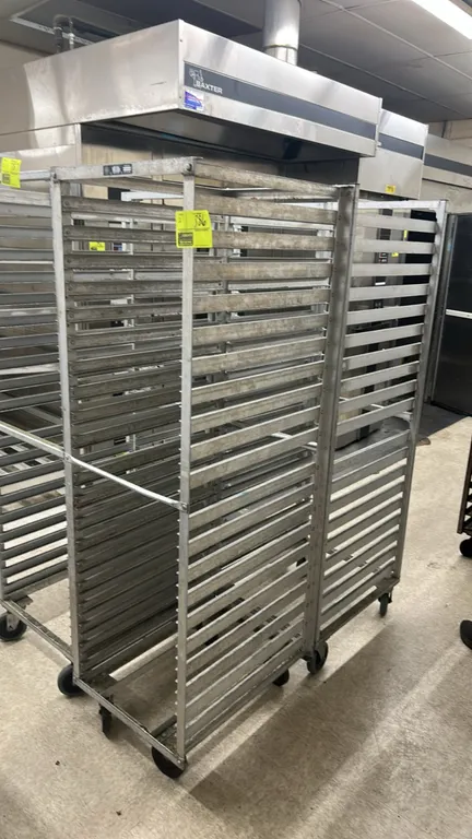 Winholt metal front-load channel pan racks. Features aluminum construction with multi-tier pan slides. Mounted on swivel casters.