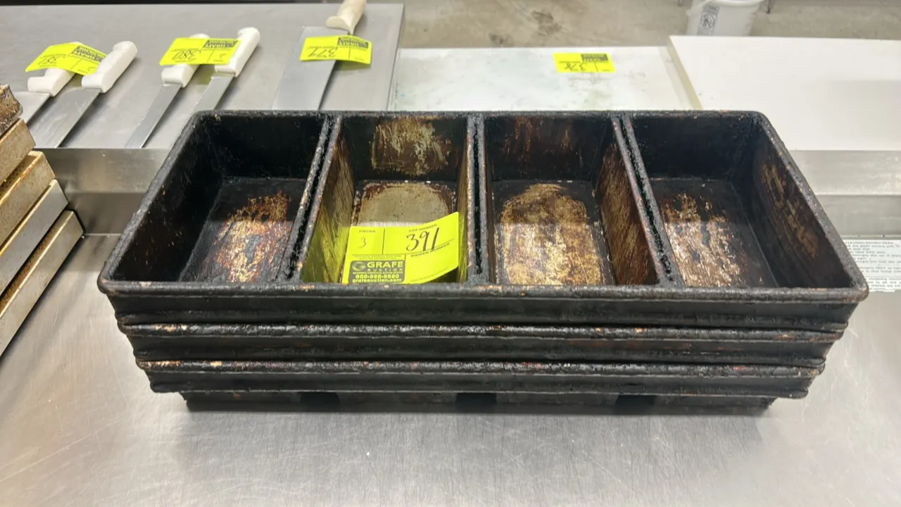 Metal 4-strap loaf pans. Features 4-compartment strapped construction designed for commercial bread baking.