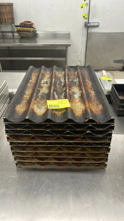 Metal 5-channel baguette baking pans. Features perforated fluted design with metal framing.