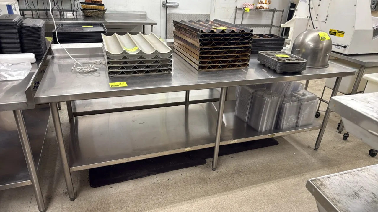 Stainless steel work table. Features a rear backsplash, full lower undershelf, and 6 tubular legs with adjustable bullet feet. Dimensions: 96"W x 36"D