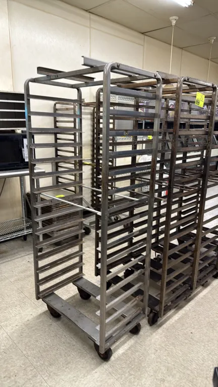 Side-load oven racks. Features heavy-duty metal construction, multi-tier pan slides, and top lift brackets. Mounted on swivel casters.
