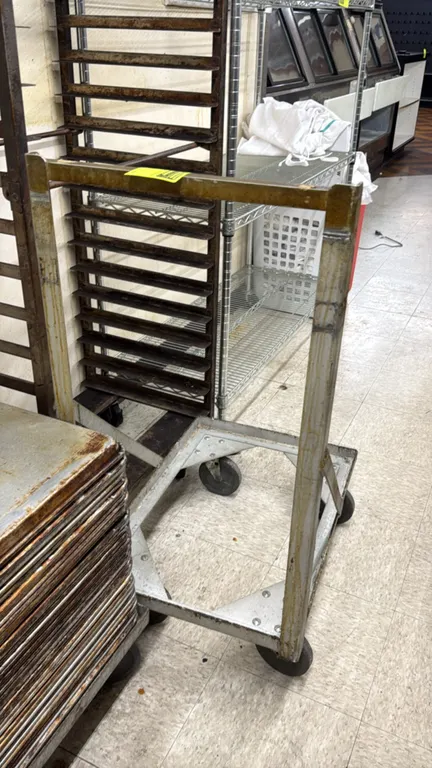 Metal sheet pan dolly. Features open-frame base with tubular upright handle. Mounted on 4 swivel casters. Sheet pans and surrounding equipment not inc
