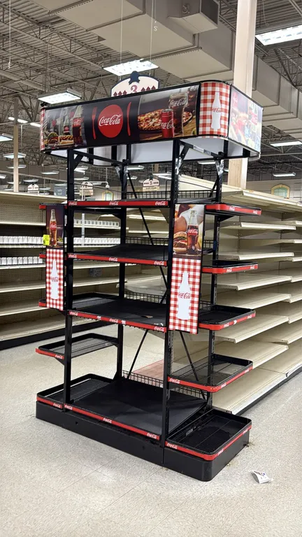 Metal Coca-Cola retail endcap display rack. Features multi-tier adjustable center shelves, side wing wire shelves, and top graphic canopy header. Dime