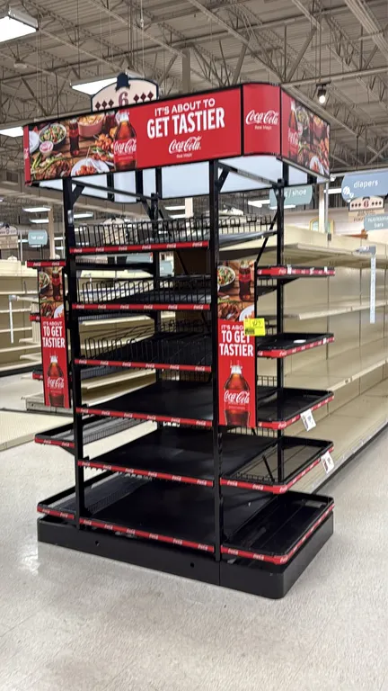 Coca-Cola branded metal retail endcap display. Features top graphic header canopy, multi-tier black wire and solid shelving, adjustable side wing shel