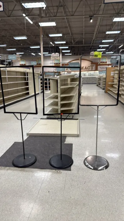 Assorted floor sign stands. Features metal construction with slide-in poster frames and round weighted bases. Includes (2) black finish and (1) chrome