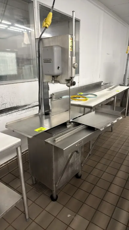 Hobart 5614 vertical meat bandsaw. Features stainless steel construction, sliding carriage table, stationary table, and adjustable blade guard. S/N: 2