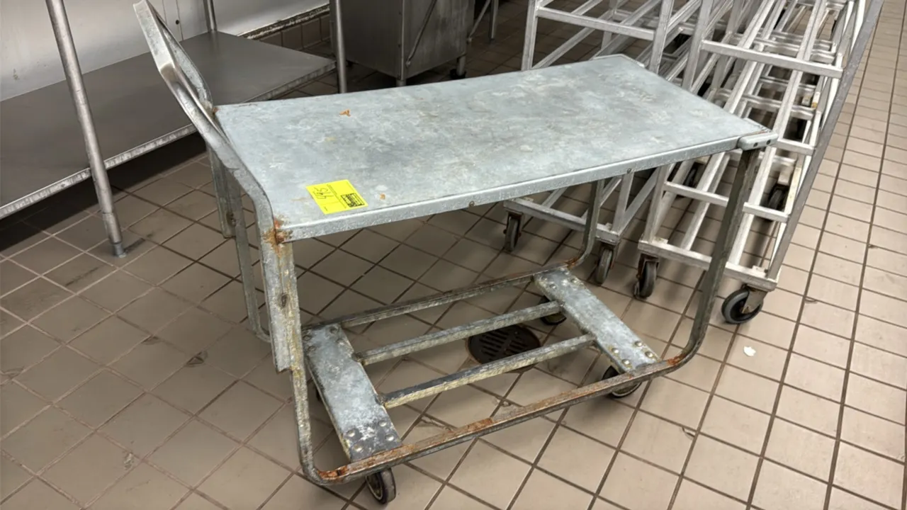 Metal 2-tier stock cart. Features a solid galvanized top shelf, integrated tubular push handle, and open lower frame base. Mounted on casters.