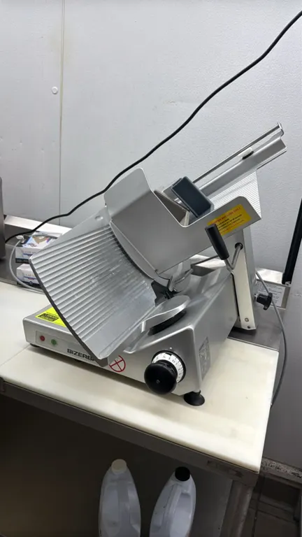 Bizerba GSP V deli slicer. Features gravity feed carriage, product pusher, adjustable thickness dial, and blade guard. S/N: 11233868. Electrical: 120V
