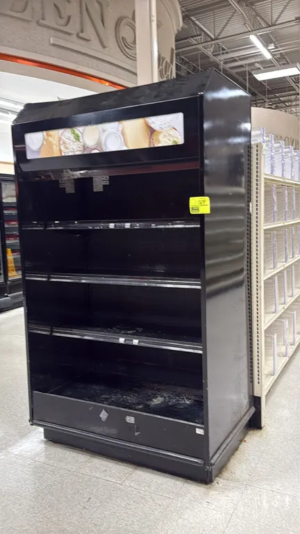 2004 Barker self-contained refrigerated 4-deck merchandise case. Features an illuminated canopy header, 3 adjustable metal shelves with price tag mold