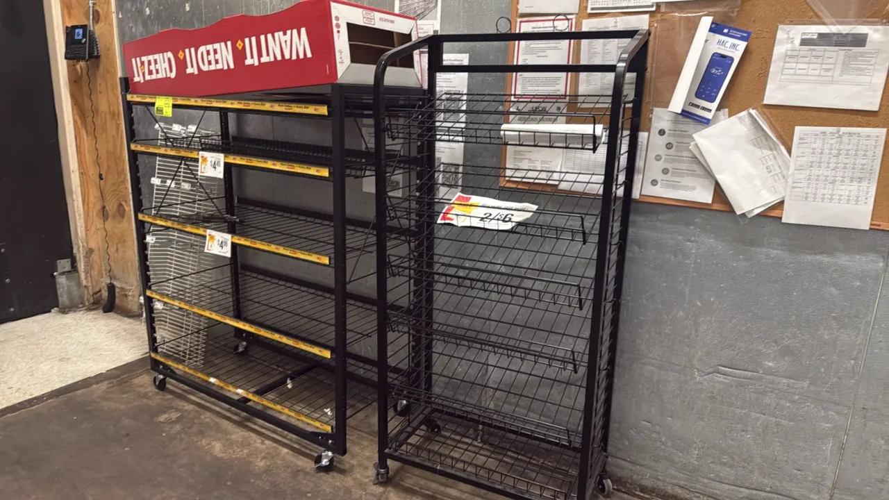 Portable metal merchandise display racks. Features black metal construction with multi-tier wire shelving. Mounted on swivel casters.