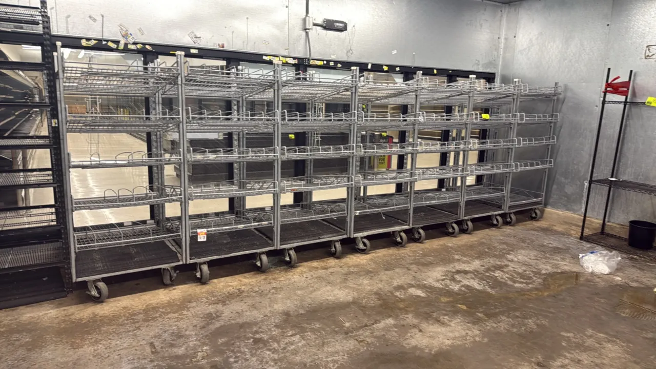 Galvanized metal mobile cooler door gravity-feed display racks. Features multi-tier angled wire shelves with integrated product lane dividers. Mounted