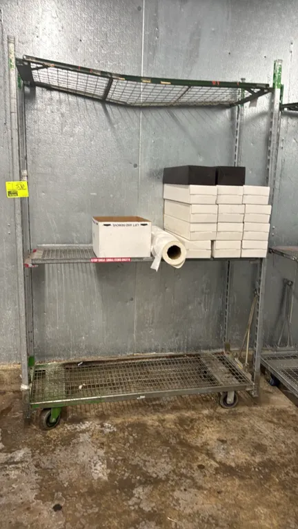 Metal portable rack. Features 3-tier wire grid shelving. 56" x 81". Mounted on casters. Contents not included.