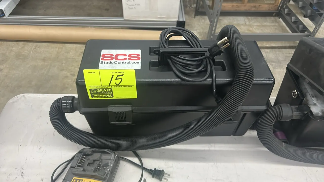 SCS electronic service vacuum. Features portable toolbox-style housing with integrated carrying handle, latched lid, flexible hose, and attached power