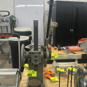 Manual ratchet-type arbor press. Features a ratcheting lever handle, side handwheel for rapid ram positioning, slotted anvil plate, and bench-mount ba