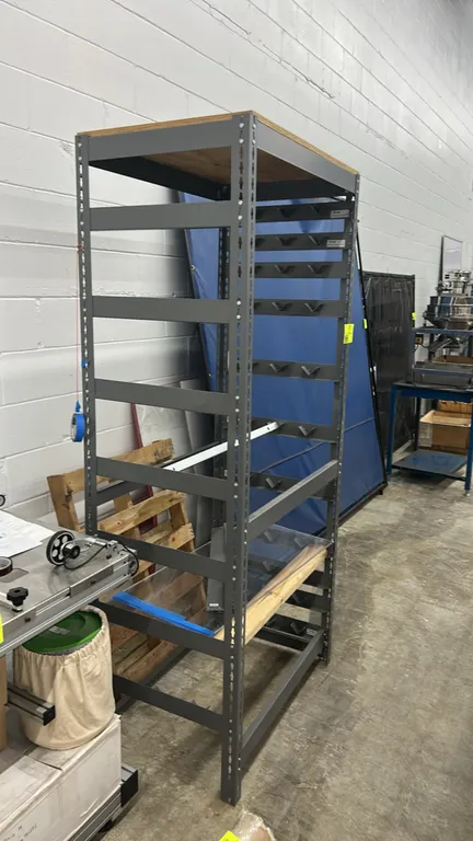 Metal multi-tier equipment rack. Features steel upright construction with multiple side support tiers, top wood shelf surface, and adjustable frame le