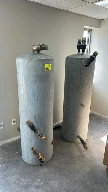 Hydro-pneumatic pressure tanks. Features vertical galvanized steel construction with assorted plumbing fittings, ball valves, and pressure port.