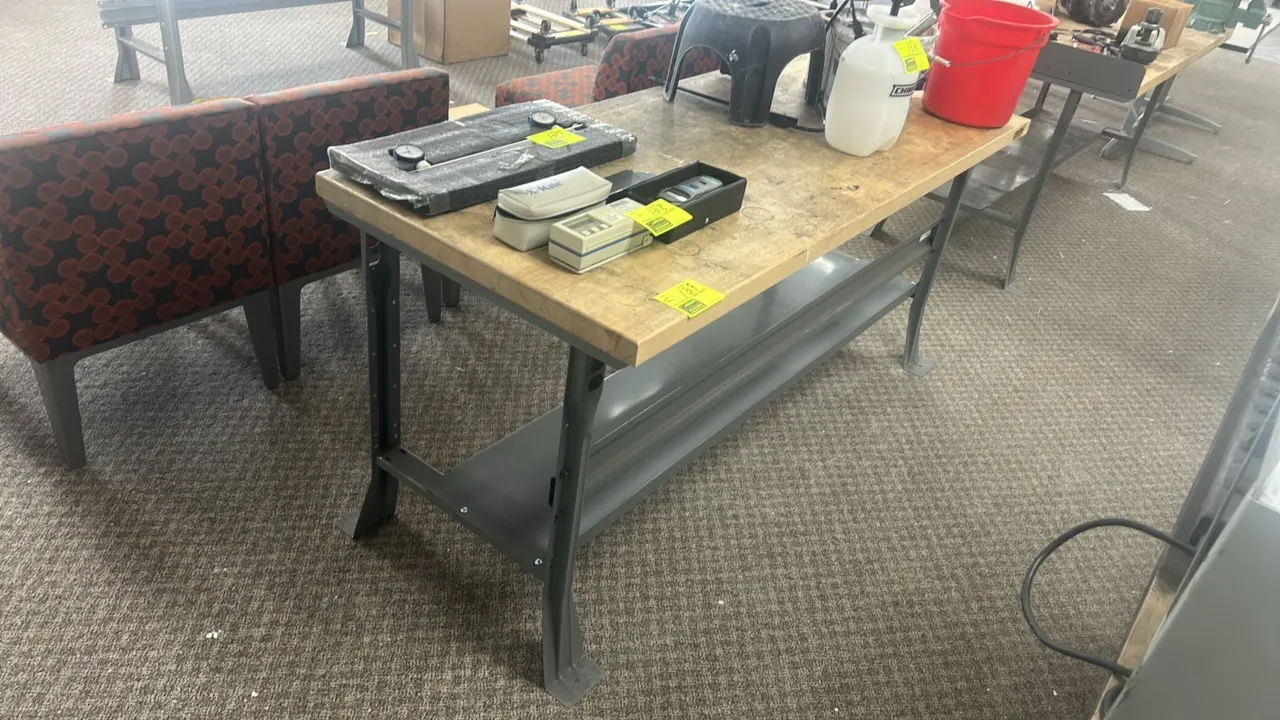 Industrial wood-top workbench. Features a solid wood top, lower metal undershelf, and gray painted steel frame and legs. 72"L x 30"W. Contents not inc