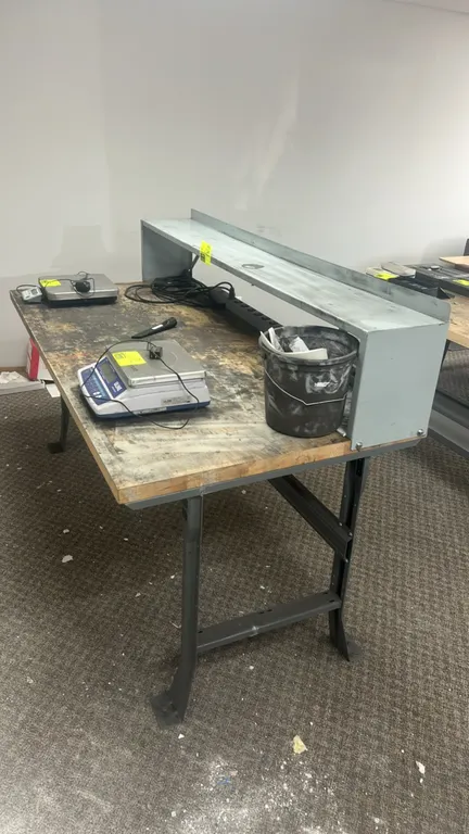 Industrial wooden workbench with over shelf. Features a solid wood top, steel frame and legs, metal upper riser shelf, and rear-mounted power strip. 6