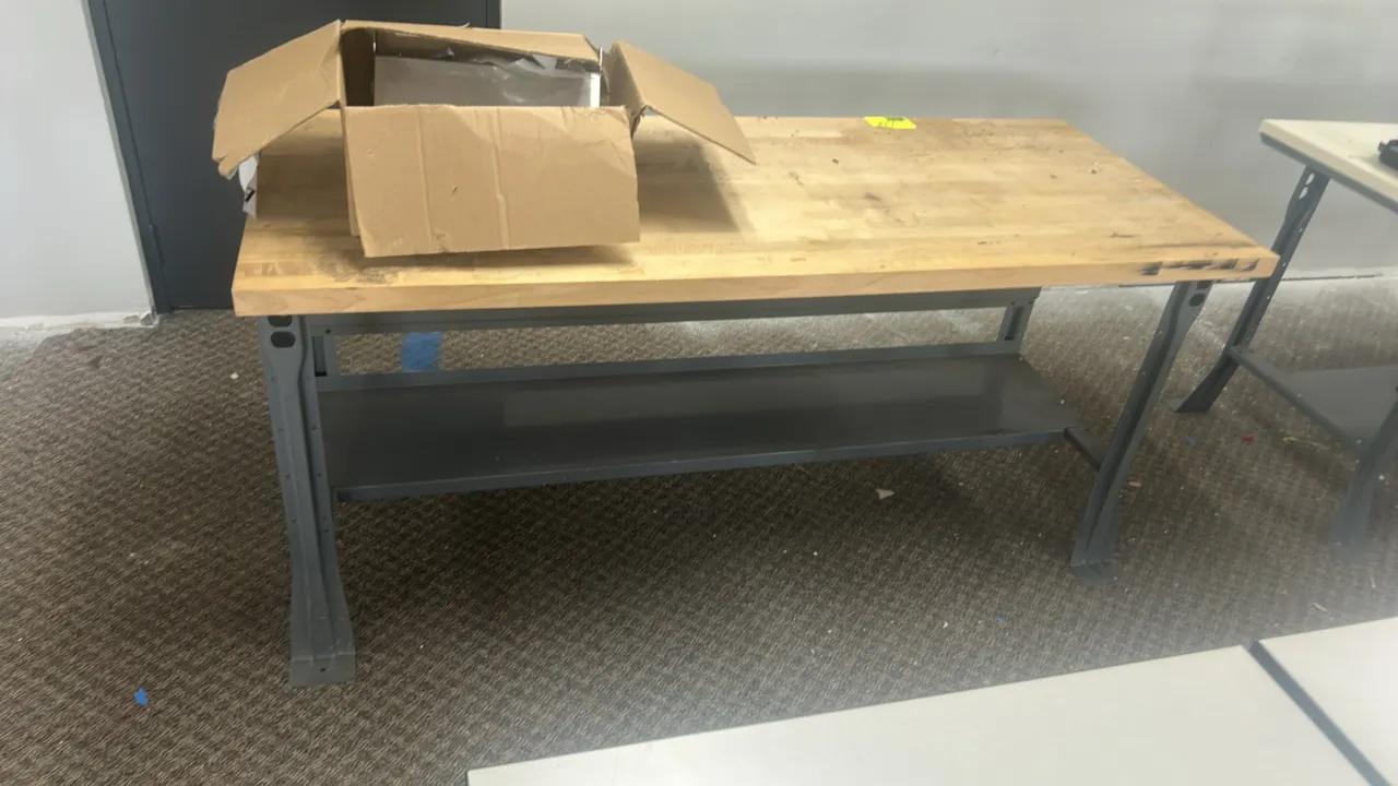 Work table with wood top. Features lower metal undershelf and gray metal frame. 72" x 30". Contents not included.