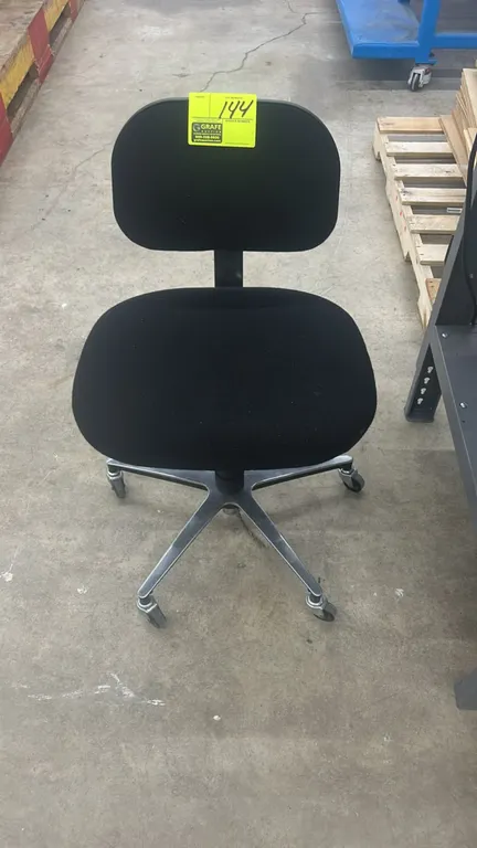 Rolling office task chair. Features black upholstered cushioned seat and backrest, armless design, and pneumatic height adjustment levers. Mounted on