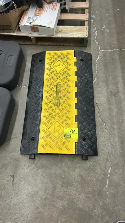 Rubber cable protector ramp. Features a yellow hinged lid, textured traction surface, interlocking modular connectors, and pre-drilled mounting holes.