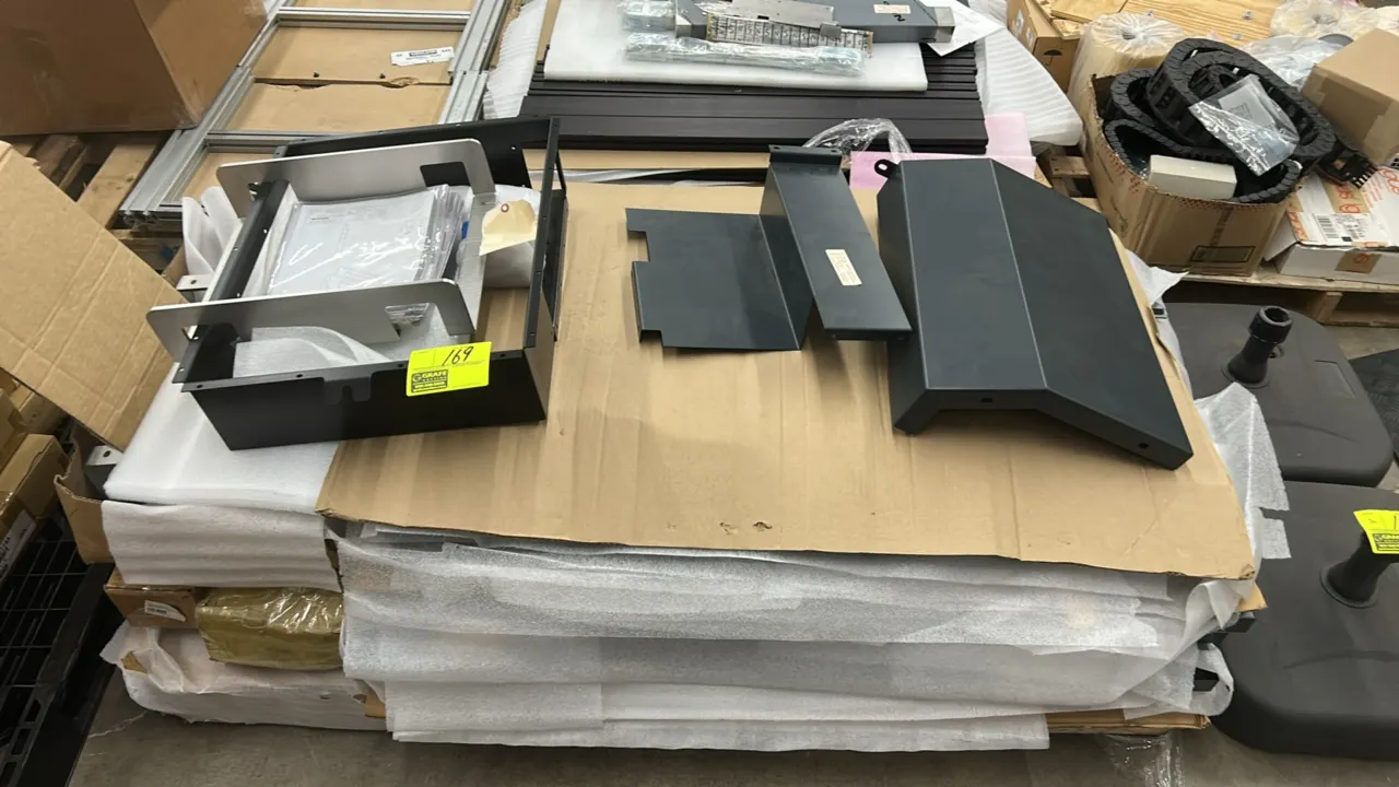 Pallet lot of assorted metal frames and sheet metal brackets. Features black coated metal housings, covers, framing components, and printed technical