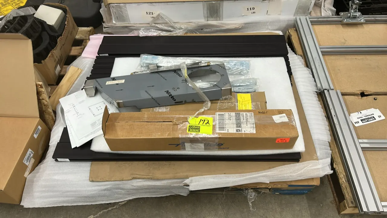 Pallet lot of assorted metal support bars, frames, and hardware. Includes dark finished metal bars, fabricated metal bracket component with protective