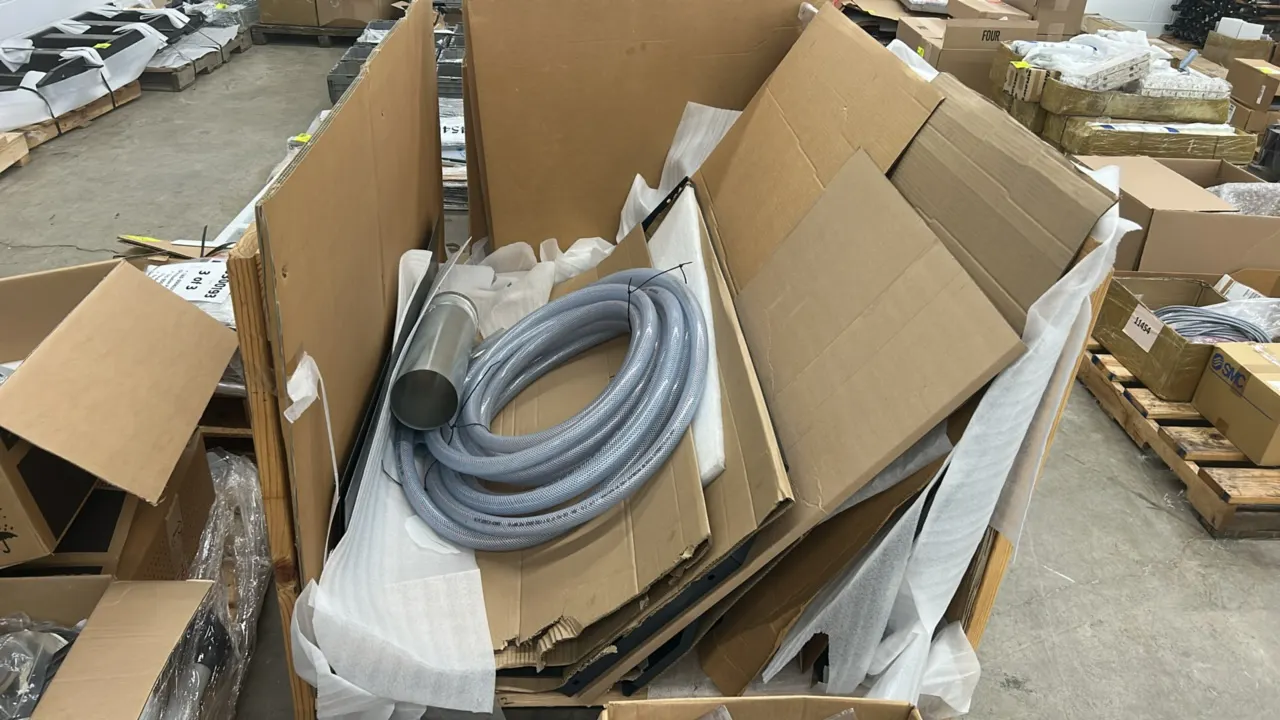 Wooden crate with metal frames and hoses. Includes coiled flexible reinforced hose, galvanized duct pipe section, and assorted metal frame components.