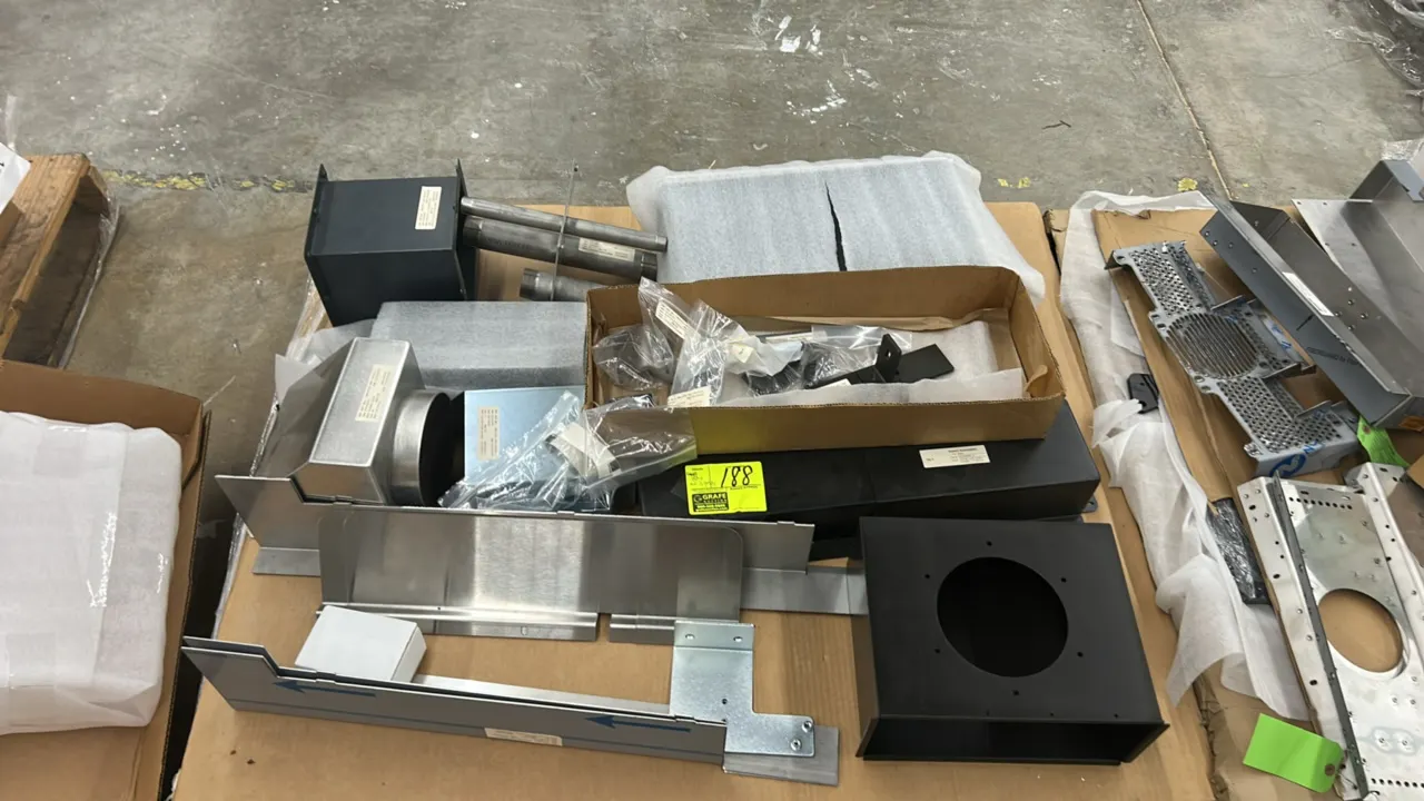 Assorted metal parts and components. Includes sheet metal brackets, duct adapters, mounting plates, pipe sections, hardware, and fabricated assemblies