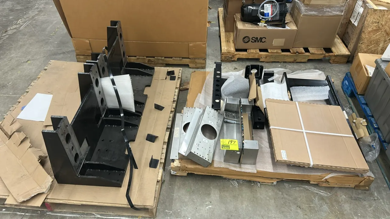 Assorted metal frames and fabrication components. Includes welded steel base frames, fabricated sheet metal brackets, and structural supports across (