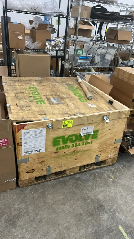 Wooden shipping crate. Features plywood construction, metal latches, and an integrated pallet skid base. 4' x 4'. Contents not included.