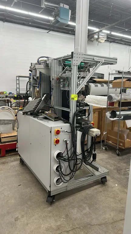 Modular industrial automation test stand. Features T-slot aluminum extrusion framing, integrated lower enclosure cabinet, pneumatic actuators, roller