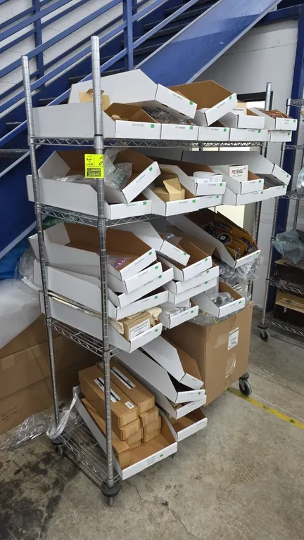Portable 4-tier chrome wire shelving unit. Includes an assortment of industrial components, parts, cabling, cooling fans, halogen lamps, sensors, and
