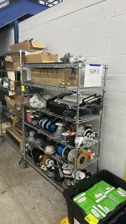 Metro mobile wire shelving rack with contents. Includes spools of wire, industrial friction-driven roller coder, liquid-cooled aluminum cold plate wit