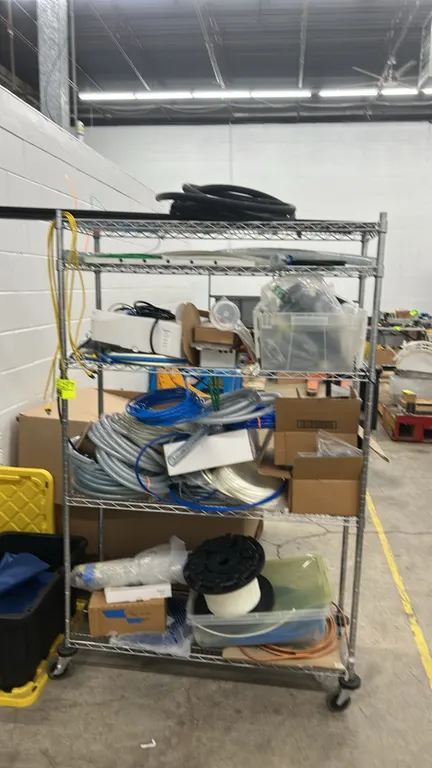 Multi-tier metal wire portable rack with assorted HVAC materials. Includes 5-tier wire shelving, assorted tubing, hoses, spools, fittings, and hardwar