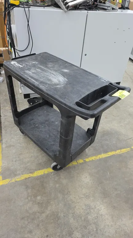 Rubbermaid poly utility cart. Features a 2-shelf design, molded plastic construction, and integrated push handle with built-in storage bin. 38" x 19".