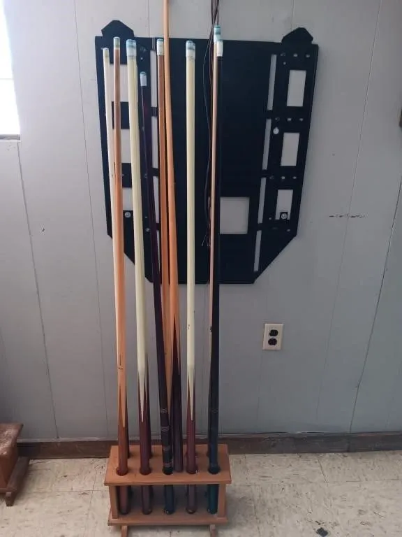Assortment of pool cues and floor stand