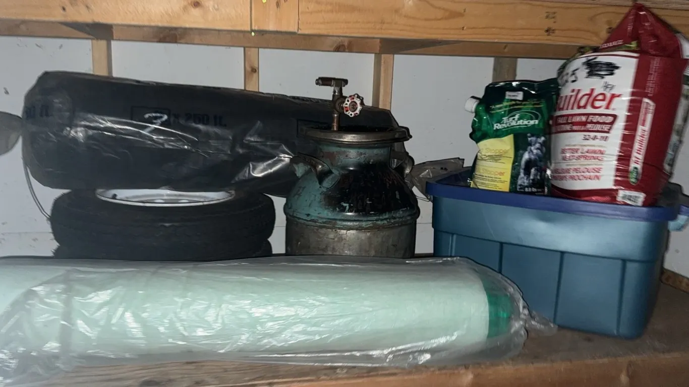 Garage Lot with Tires, Milk Can, Lawn Fertilizer, and Blue Storage Bin