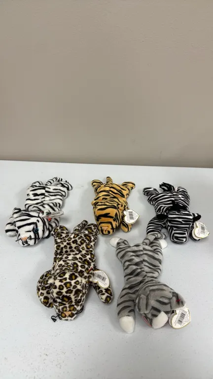 A Collection of Ty Beanie Babies Plush Toys. (Ty, 1990s) A five-piece collection of animal-print plush figures including a tiger, white tiger, zebra,
