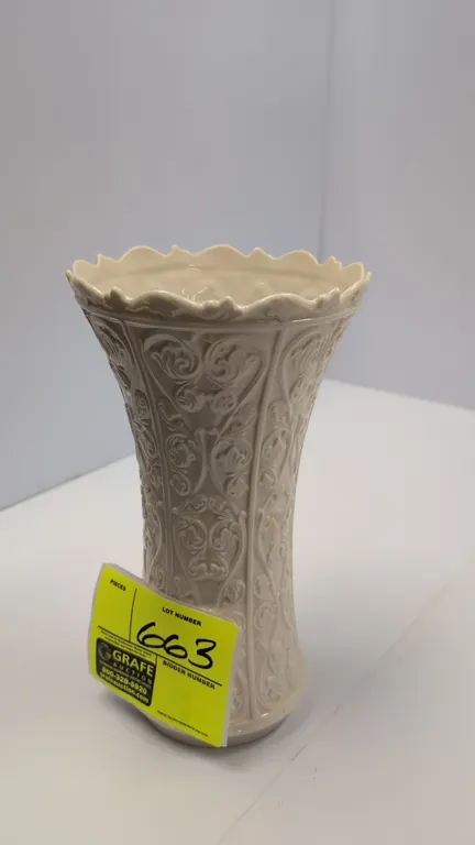 Ceramic vase. Features an off-white glazed finish, embossed floral scrollwork design, scalloped rim, and flared top. 11"H.