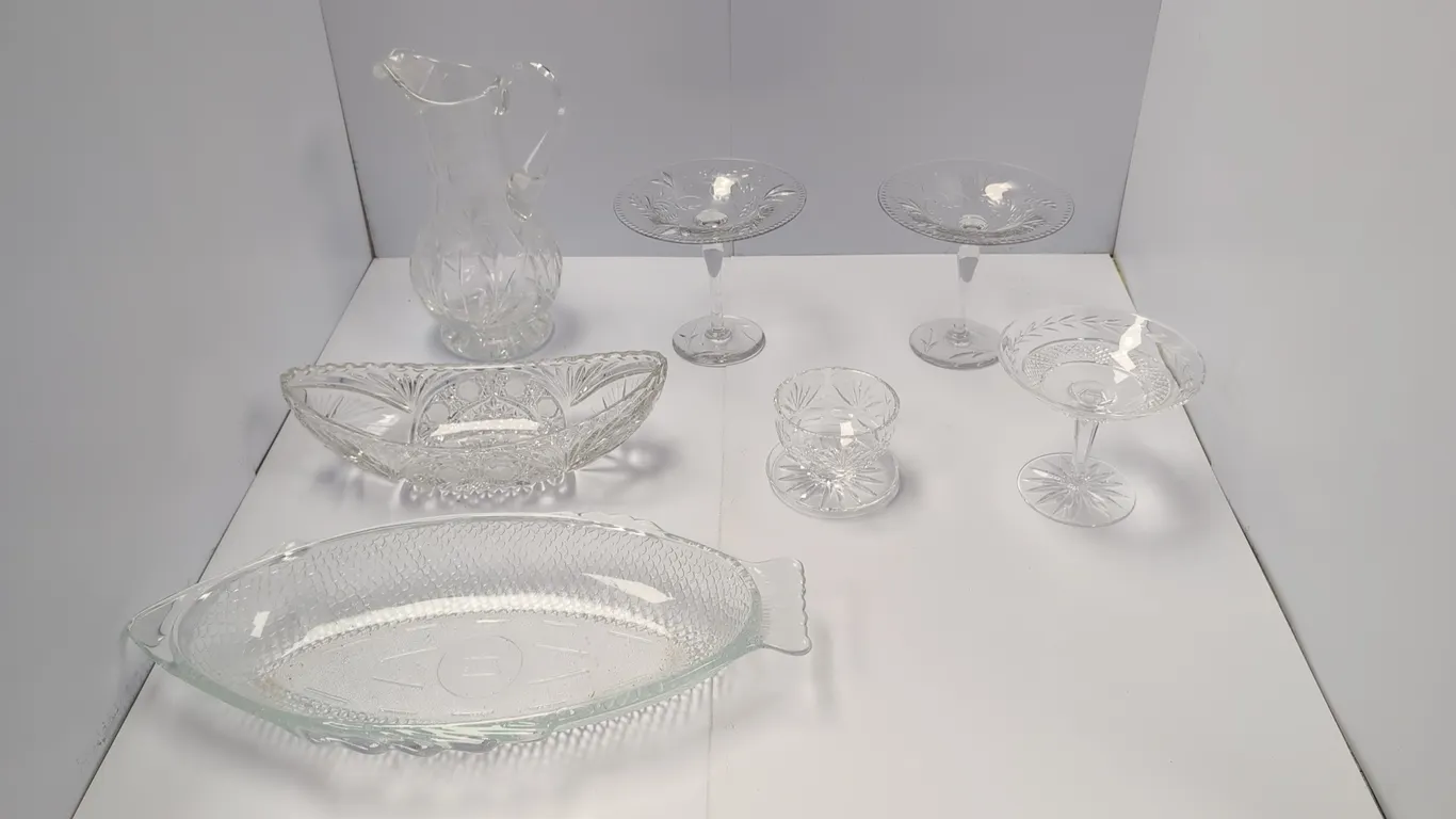 Assorted crystal and glass tableware. Includes a handled pitcher with floral etching, three stemmed pedestal compotes and candy dishes with etched det