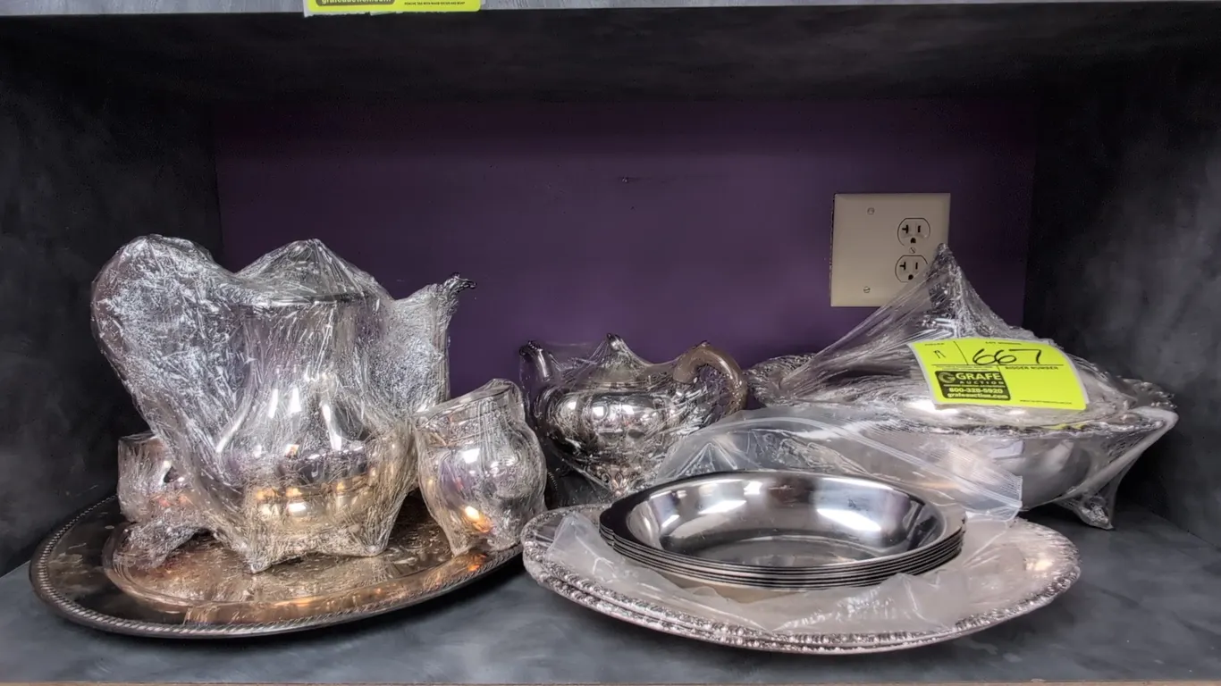 Assorted decorative metal and silver-plated dishware. Includes teapots, coffee pot, creamers, covered sugar bowls, footed serving dishes, covered cand