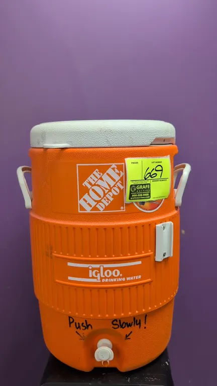 Igloo 5-gallon insulated beverage cooler. Features side carry handles, push-button dispensing spigot, Home Depot branding, and side cup dispenser brac