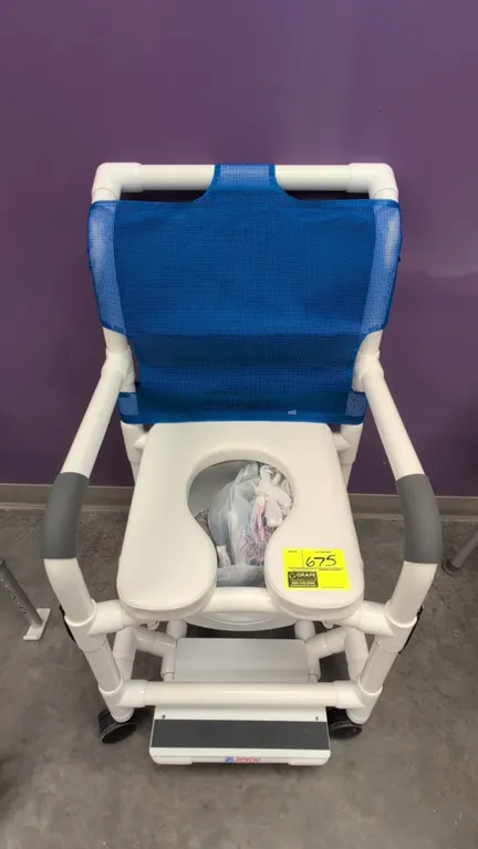 Portable PVC commode chair with Kangaroo enteral feeding pump. Commode features PVC pipe frame, padded open-front seat, blue mesh backrest, slide-out