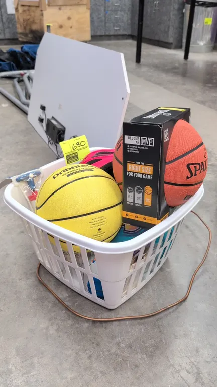 Assorted sporting and outdoor recreation equipment. Includes a boxed Spalding outdoor basketball, DribbleUp junior size basketball, pink Giro bicycle