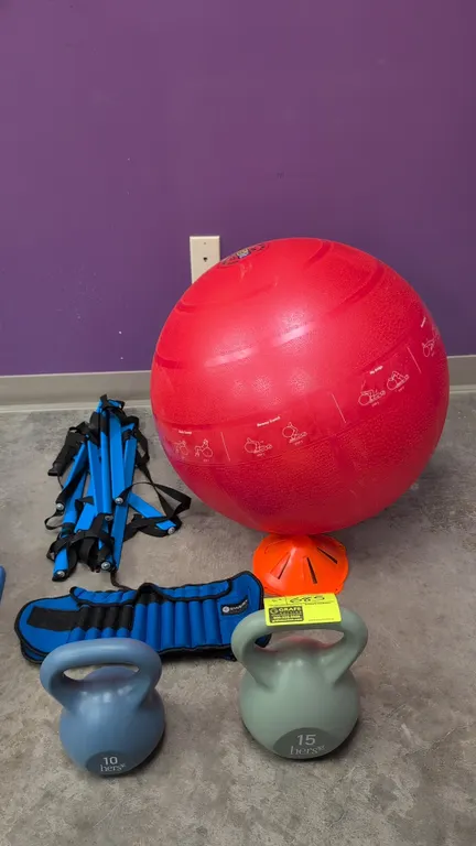 Assorted exercise equipment. Includes Hers 10 lb and 15 lb kettlebells, Gymenist weighted belt, red exercise stability ball with printed workout guide
