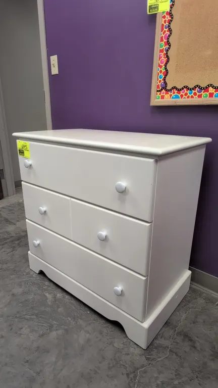 Wood 3-drawer cabinet. Features a white finish, round knobs, and a shaped apron base. Dimensions: 33" x 18" x 32".